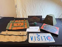 Overall lot showing Packard box, canvas pouches, spinner knob, licence plate, map cover and metal cover