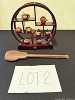 Front view of display shelf holding nine miniature teapots with wooden paddle in foreground
