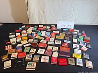 Top-down view of entire lot showing assortment of matchbooks spread on black surface