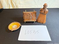 Front view of porcelain ashtray, carved plaque on stand and whisk broom