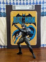 Figure posed in front of Batman metal sign