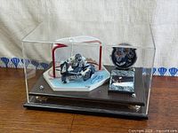 Overall view of signed figurine, puck, plaque inside acrylic case