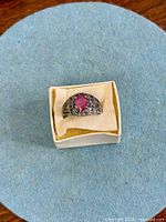 Ring in box, top view showing pink sapphire and blue sapphire accents