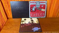 All three Eagles album covers displayed on wood surface