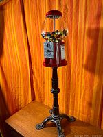 Full view of red gumball machine on stand
