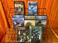 Front view of six Warhammer/Imperial Armour books on wire rack