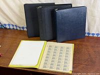 Four binders, one open showing stamp pages