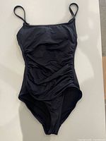 Front view of black one-piece swimsuit showing ruched sides and straps