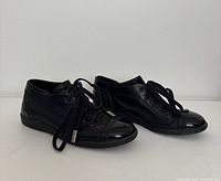 Side view of both sneakers showing leather uppers, patent toe caps, rubber soles