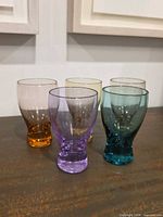 Five multicolor glasses grouped on table