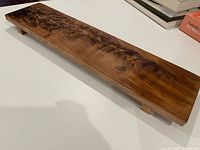 Oblique view of walnut board on feet