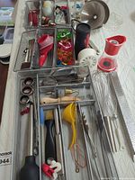 Overview of four mesh trays filled with assorted utensils and gadgets