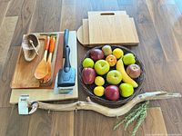 Group shot of entire lot on floor including cutting boards, utensils, meat mallet, faux fruit basket and driftwood