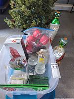 Storage tote with ornaments, jars, Santa figurines, tree in background