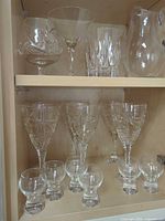 Shelf view of assorted cut crystal glassware including wine goblets and cordials