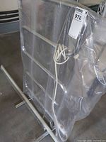Freestanding chrome ladder-style towel rack wrapped in plastic, power cord visible