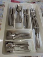 Flatware in drawer tray showing multiple place settings, beaded pattern visible