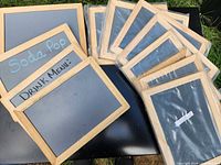 Group of twelve chalkboard signs, four unwrapped with writing, eight wrapped in plastic