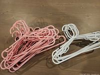 Mixed group of pink and white child-size plastic hangers on tabletop