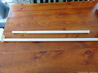 Two white adjustable rods on wooden surface