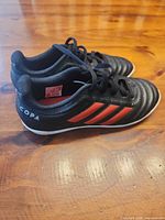 Left side view of both shoes showing black upper, red stripes, COPA heel branding.