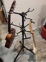Full view of stand holding two sample guitars, shows multiple yokes and overall structure