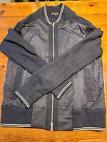 Full view of navy mixed-material Banana Republic bomber jacket laid flat