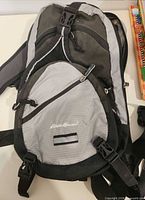 Front view of gray and black Eddie Bauer backpack showing main compartments and front zip pocket
