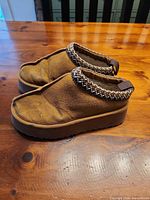 Left side view of both clogs showing suede exterior, knit trim, rubber soles
