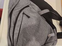 Front view of gray sling bag showing zipper pockets and fabric texture
