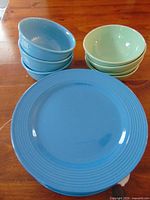 Stack of three blue bowls, stack of four green bowls, stack of blue ribbed dinner plates