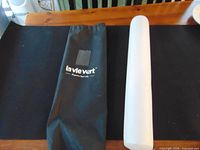 White puzzle mat cylinder and black La Vie Vert carry bag on table