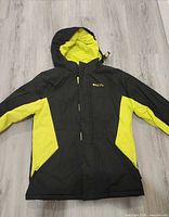Front view of black and yellow youth ski jacket