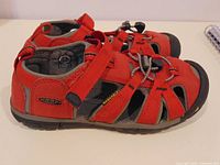 Side view of both red Keen children’s sandals showing uppers, strap, toe protection