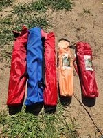 Five folded chairs in carry bags laid on ground showing colors and quantity