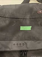 Front view of Tumi messenger bag showing flap, buckle and wear