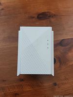 Front view of white plug-in Wi-Fi extender showing textured panel and LED indicators