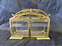 Front view of brass and glass letter holder showing two compartments and decorative crest