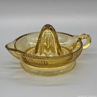 Front angled view showing amber glass juicer with handle, spout, base
