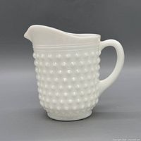 Front view of white milk glass hobnail pitcher