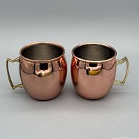Front view of both mugs showing copper exterior and handles