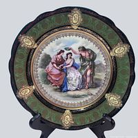 Full view of plate on stand showing entire design, border, and central scene