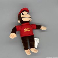 Front view of Curious George plush showing face, cap, and shirt logo
