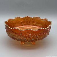 Side view showing exterior raised floral pattern, feet and marigold iridescence