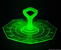 Tray glowing bright green under UV showing uranium content