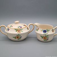Sugar bowl with lid and creamer side by side showing pattern and trim