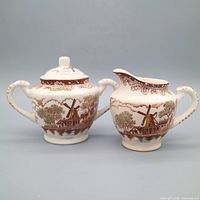 Front view of creamer and sugar bowl displaying windmill scene