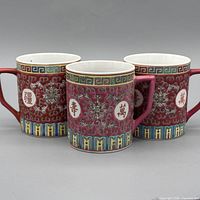 Front view of three matching red famille rose mugs