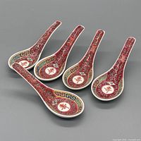 Five red famille rose Chinese soup spoons arranged on grey background