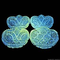 Four clear pressed cut glass bowls glowing green under UV light